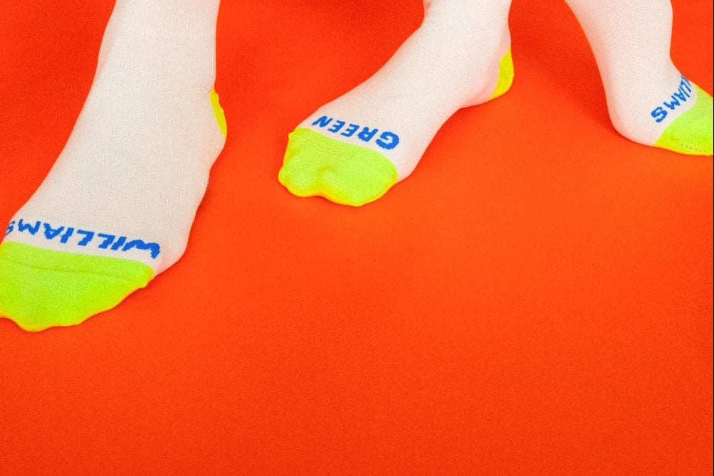 White socks with green accents worn by a person on an orange background.